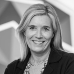 Zwart-witfoto: een lachende vrouw met golvend haar draagt een blazer tegen een geometrische achtergrond.