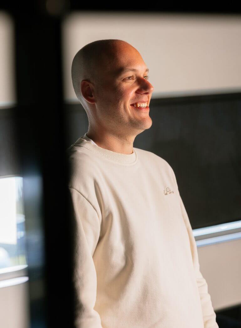 Een warme glimlach in een witte trui, zachtjes gloeiend in een donkere kamer.