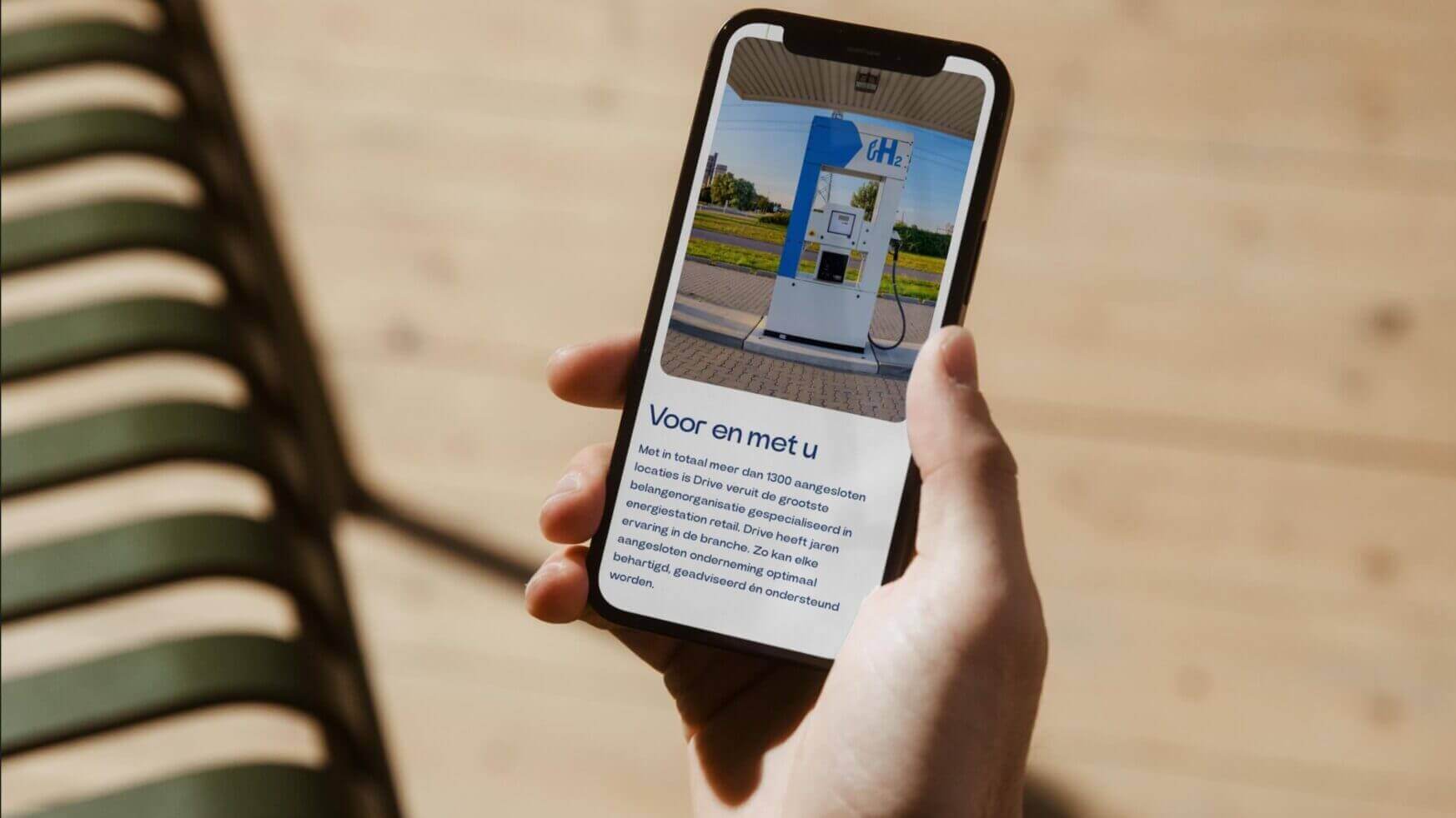 Persoon toont smartphone met afbeelding en informatie over een CNG-tankstation.