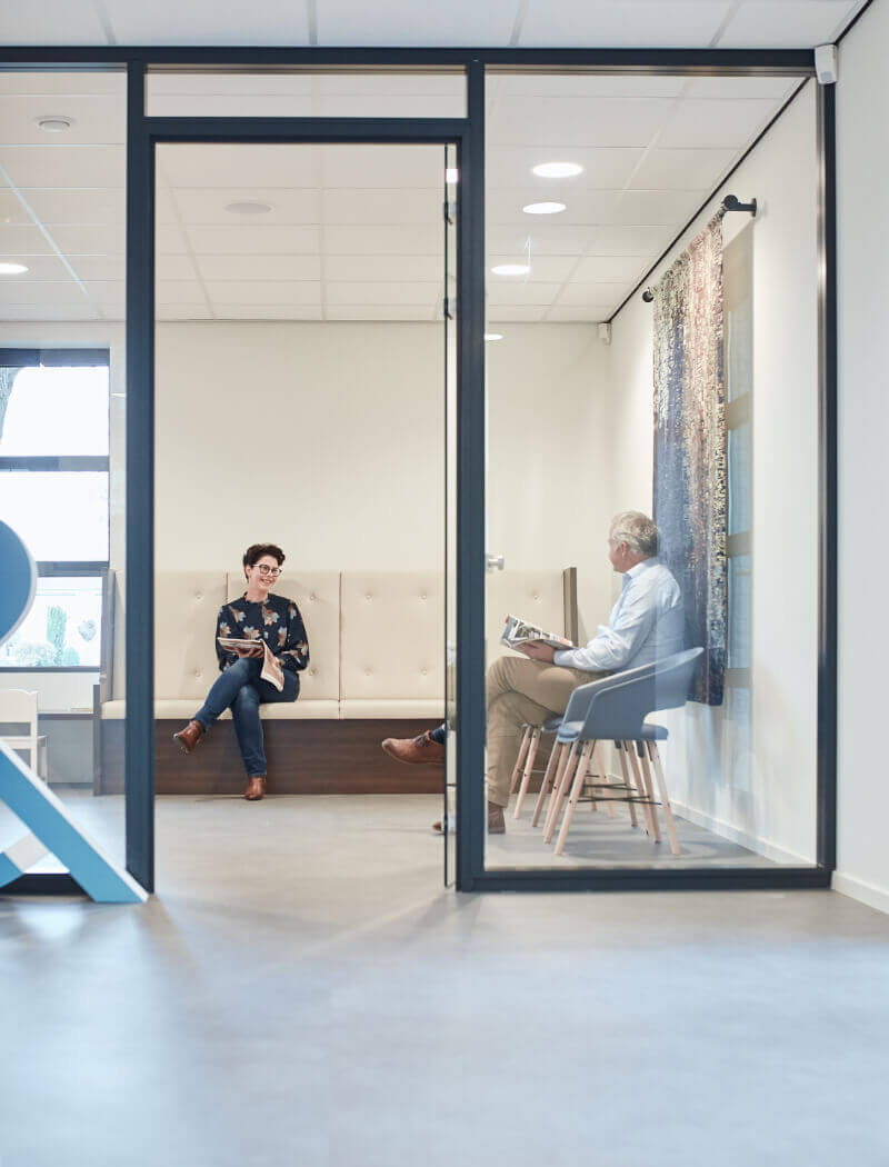 Twee mensen kletsen in een strak kantoor met glazen wanden en een helder, minimalistisch design.