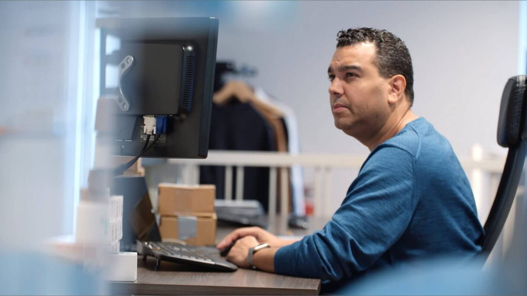 Een man in een blauw overhemd gebruikt Touchfix op zijn computer om taken op kantoor efficiënter te stroomlijnen.