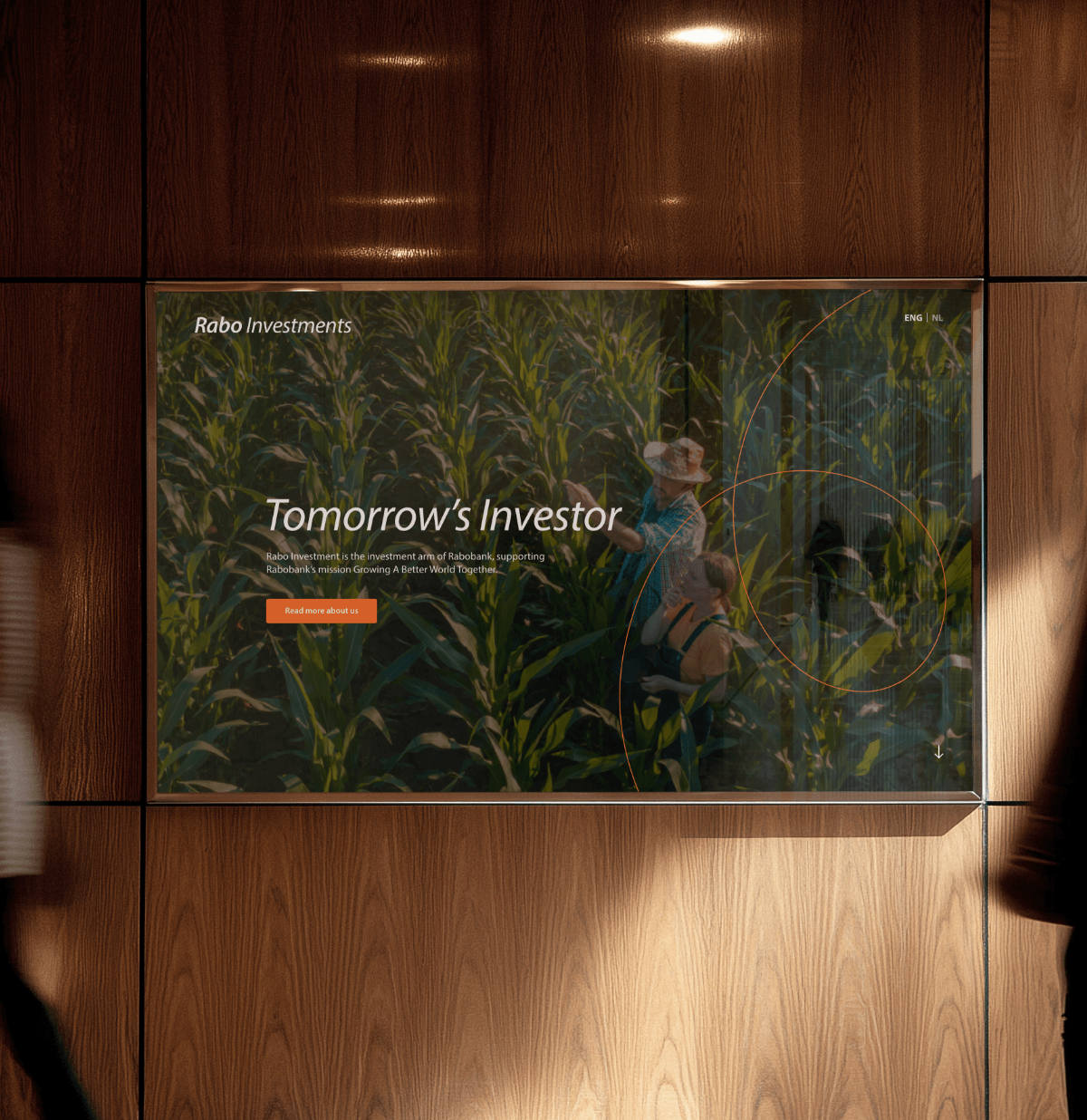 Digitaal scherm op houten muur toont advertentie voor investering in boerderij; twee mensen lopen ervoor langs.