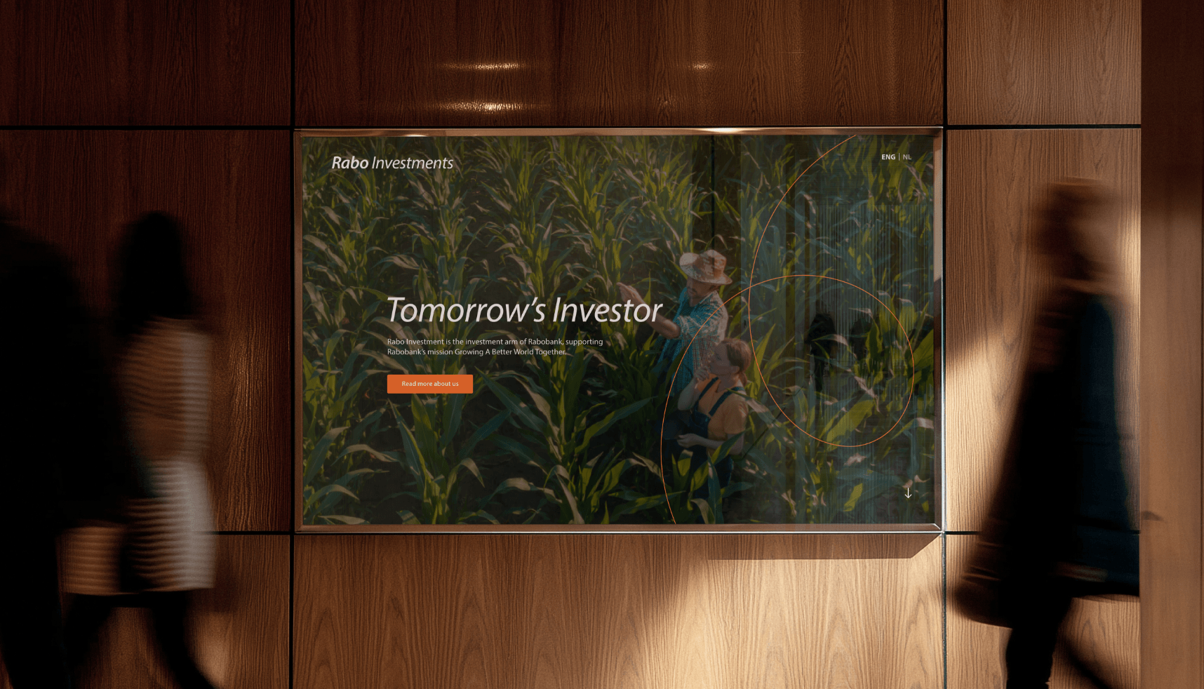 Digitaal scherm op houten muur toont advertentie voor investering in boerderij; twee mensen lopen ervoor langs.