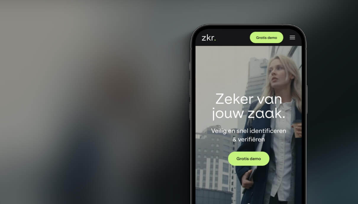 Smartphone toont app met Nederlandse tekst; zakenvrouw zichtbaar erachter.