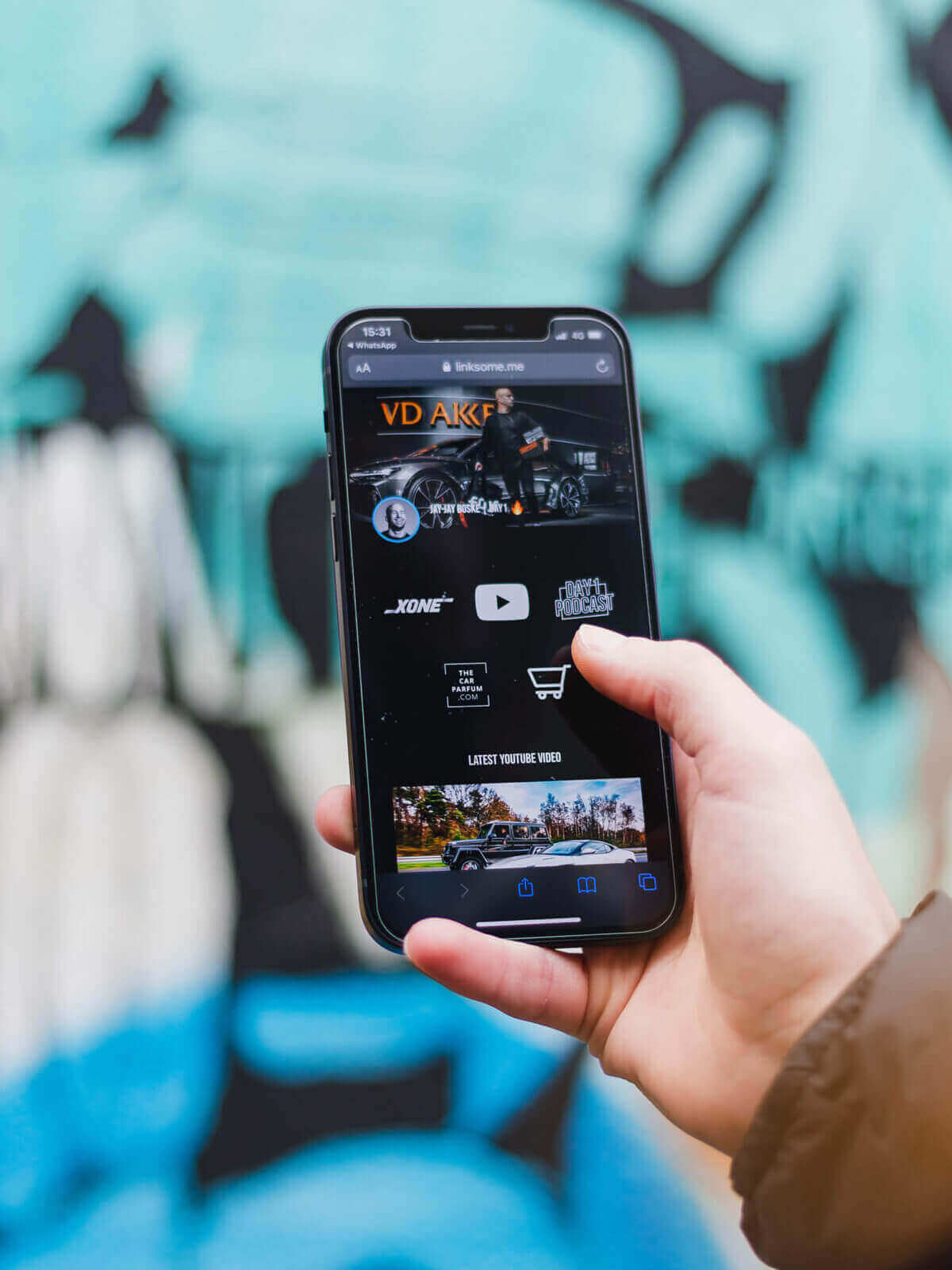 Smartphone met video en winkelwagentje tegen een blauwe graffitimuur.