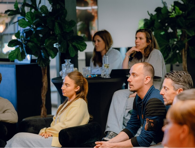 Mensen zitten binnen, geconcentreerd en aandachtig tijdens een vergadering of presentatie.