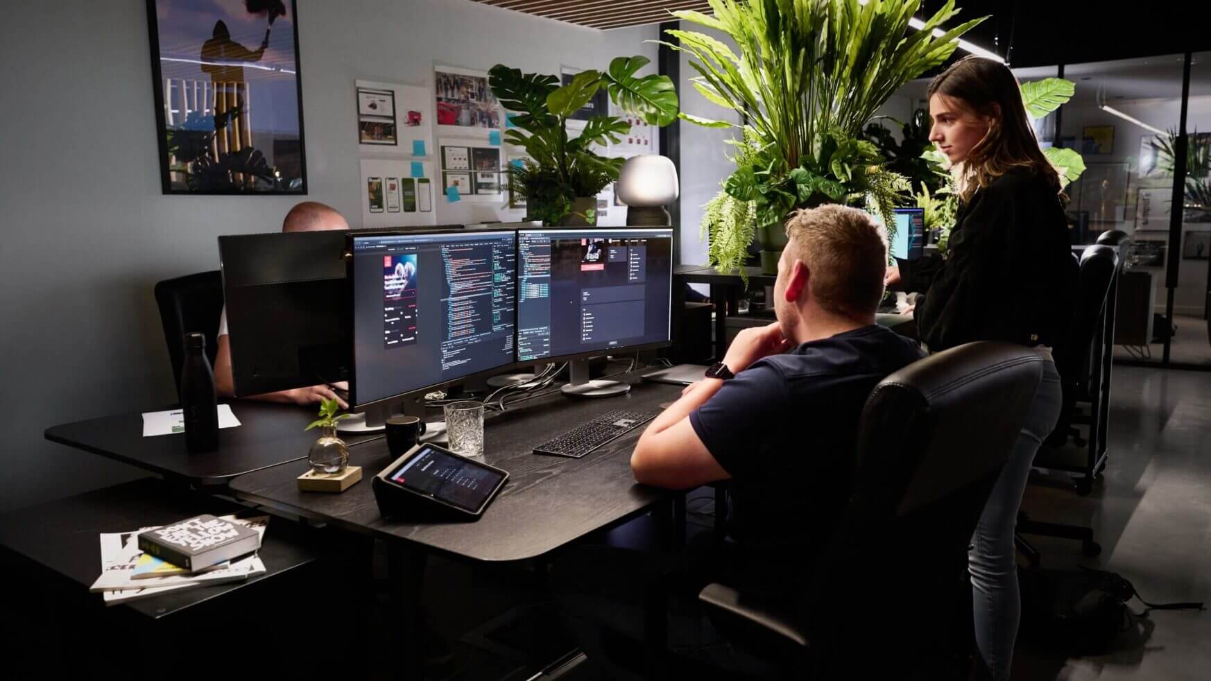 In een kantoor vol technologie en planten beheren drie mensen efficiënt koppelingen achter hun computers.