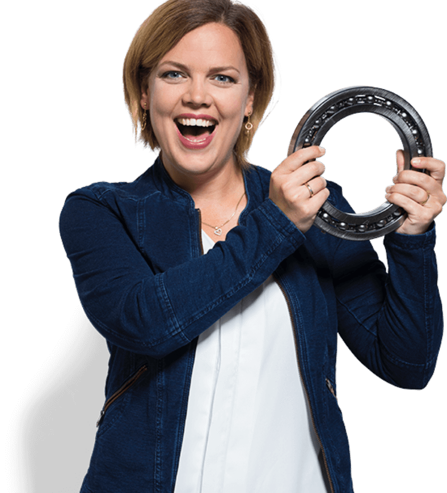 Een vrouw in een blauw jasje toont met een glimlach een ABF-onderdeel en toont daarmee haar technische vaardigheden.