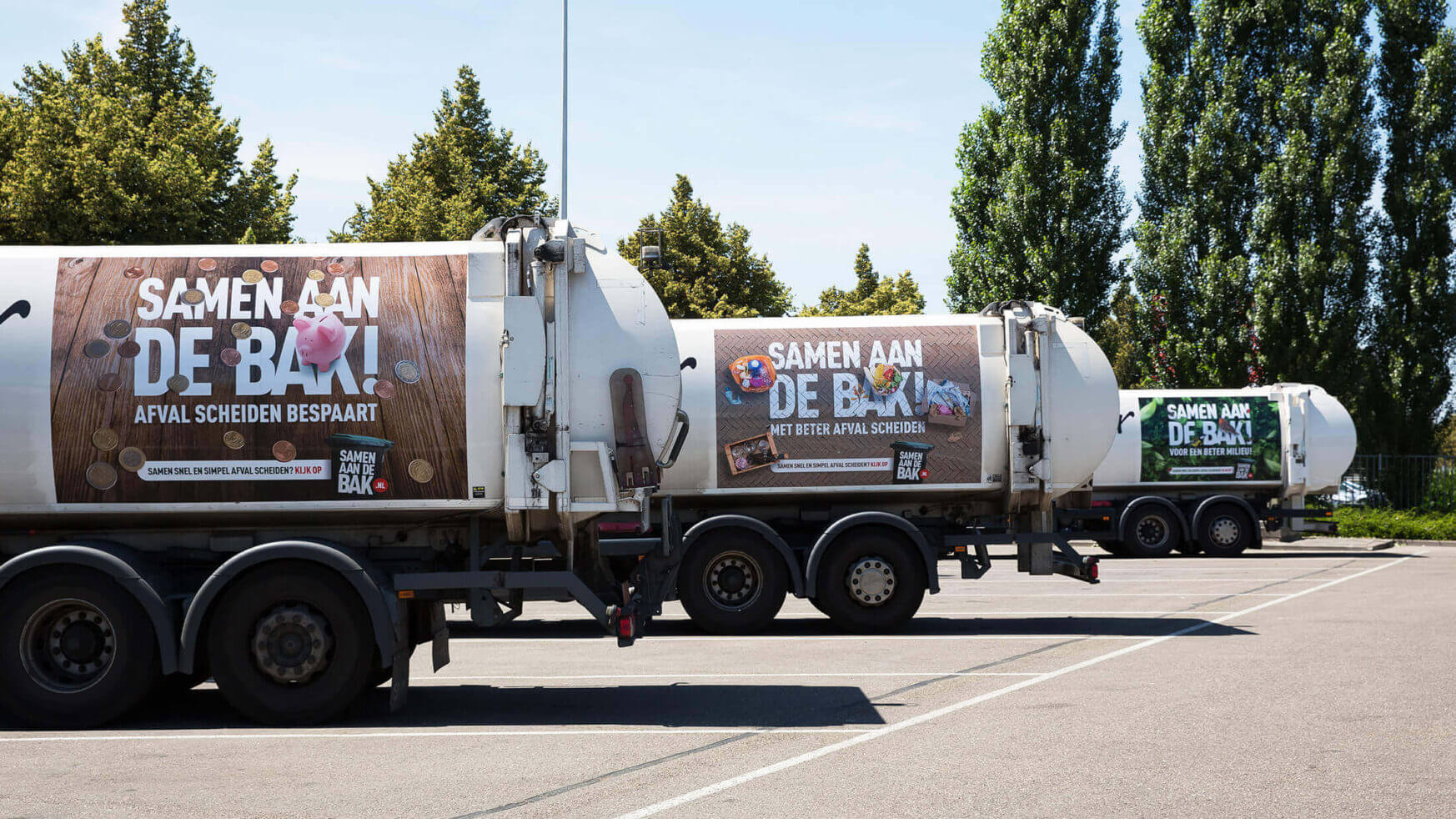 Vrachtwagens op het parkeerterrein tonen opvallende banners van de afvalscheidingscampagne Samen Aan De Bak!.