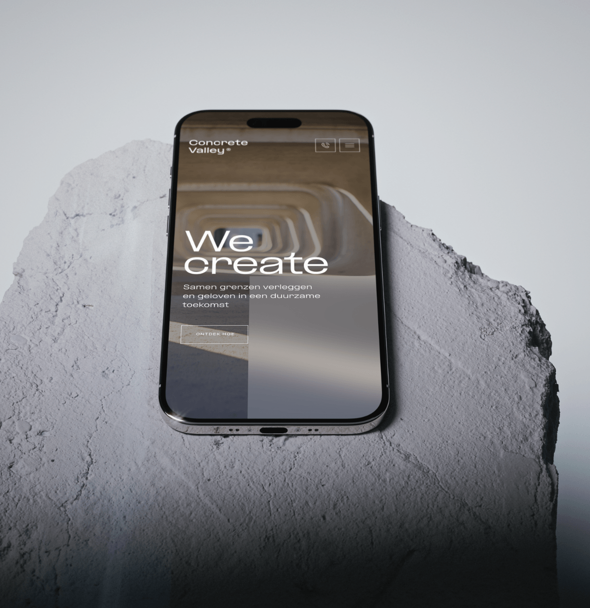 Smartphone toont de website van Koppert Cress met de tekst "We create" op een ruw, lichtgrijs stenen oppervlak.