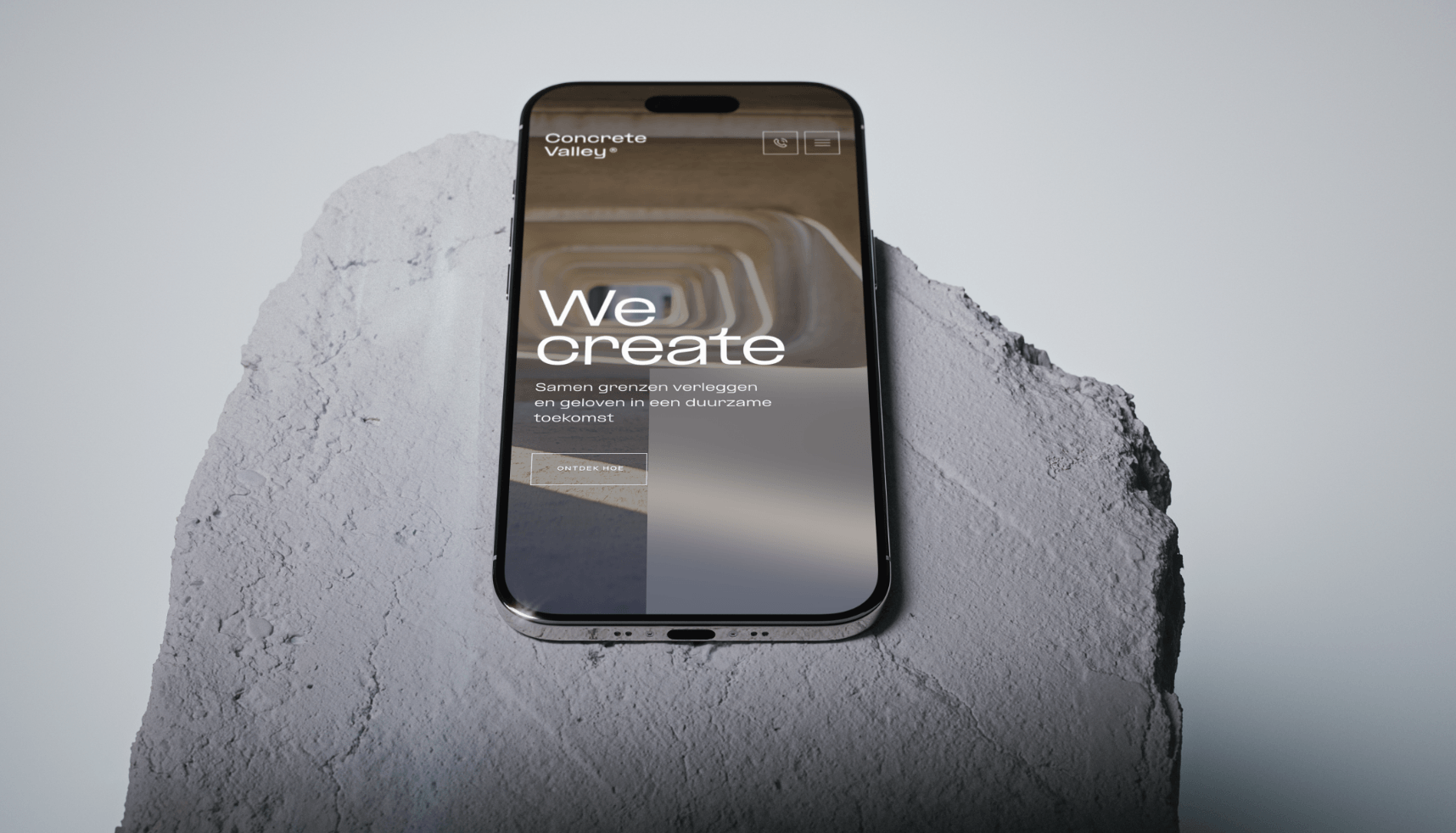 Smartphone toont de website van Koppert Cress met de tekst "We create" op een ruw, lichtgrijs stenen oppervlak.