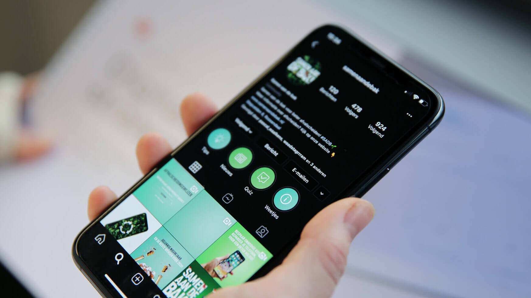 Iemand houdt een smartphone vast met daarop een Instagram-profiel vol foto's en pictogrammen, waarop zijn digitale strategie te zien is.
