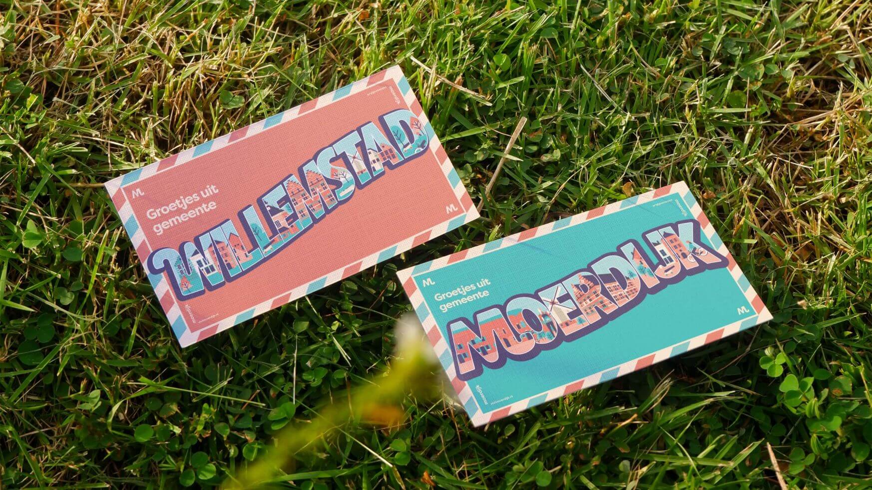 Roze en groenblauwe kaarten met vette tekst en decoratieve randen op groen gras, met een levendige Visit Moerdijk boodschap.