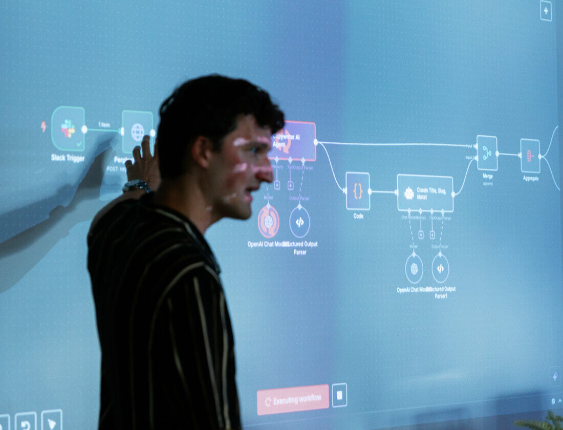 Iemand wijst op een workflowdiagram dat tijdens een presentatie op een scherm wordt weergegeven.