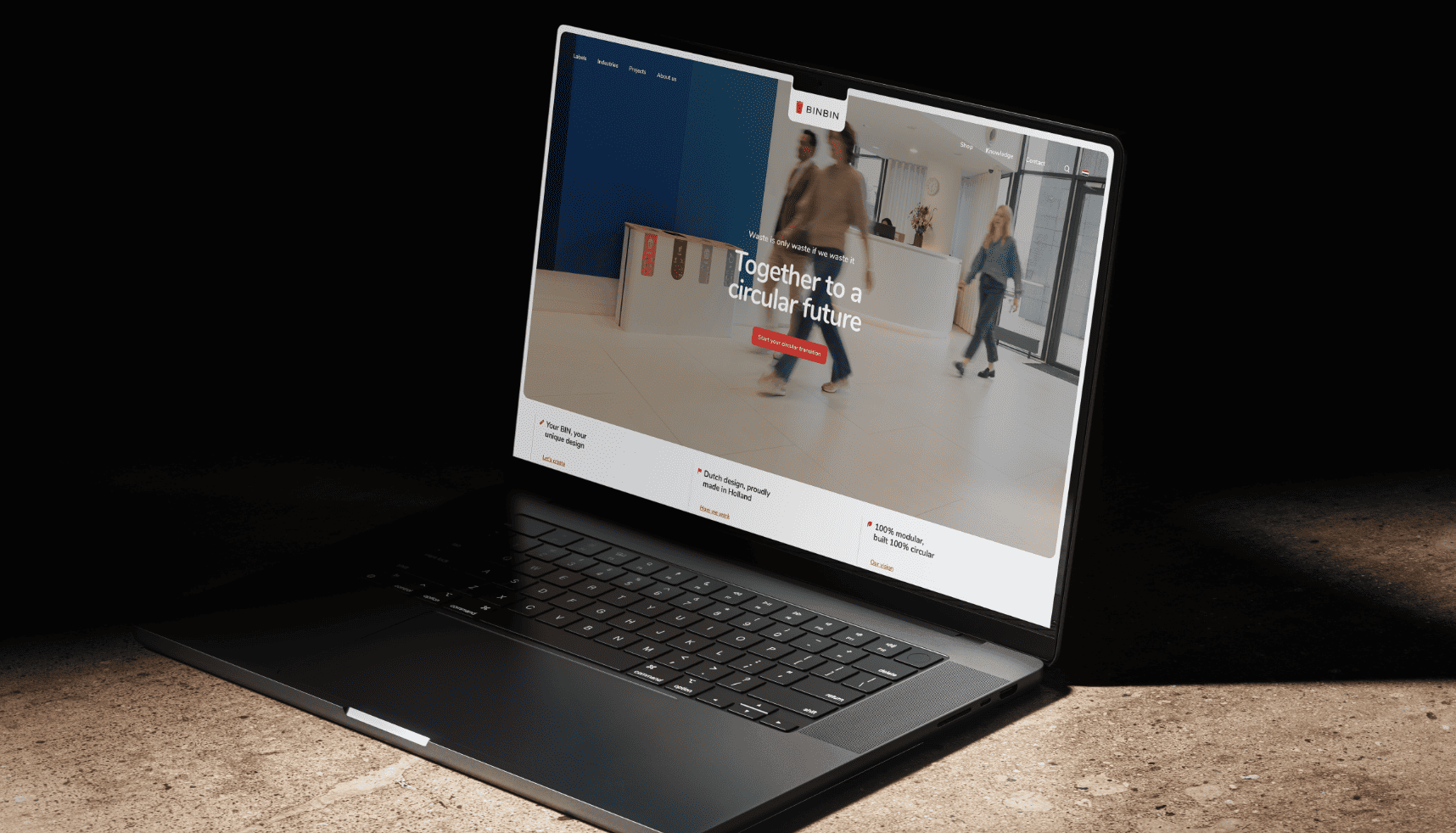 Laptop op een bureau toont een website met mensen die in een strakke, moderne lobby van een kantoor lopen.