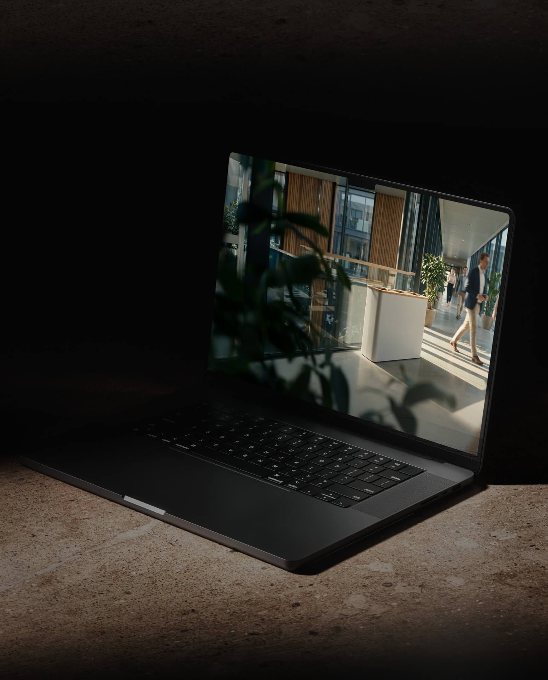 Laptop op een stenen oppervlak met een heldere kantoorscène op het scherm.