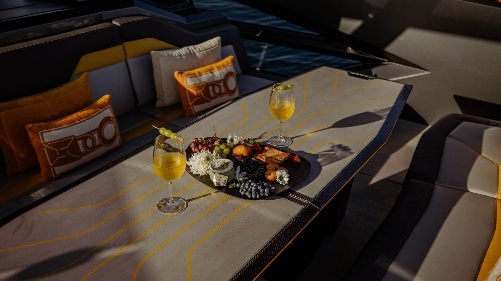 Fruit, snacks en twee gele drankjes op een tafel op een jacht.