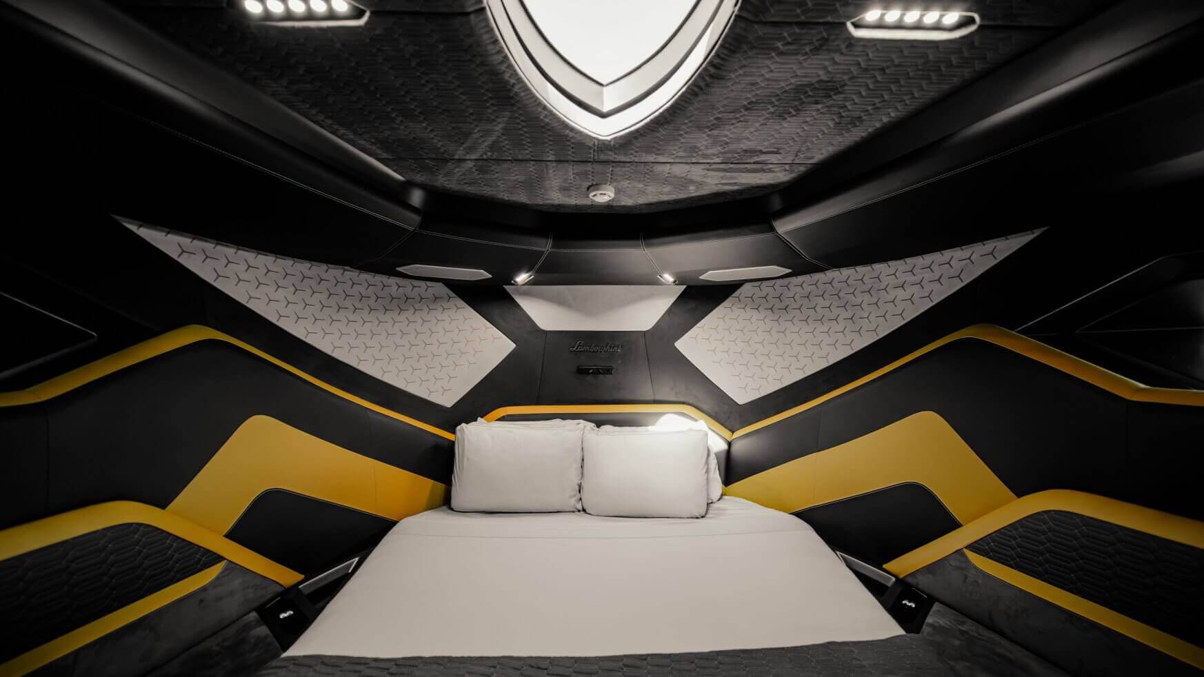 De kajuit van een Lamborghini-boot met een bed en een geometrisch geel en zwart schot.