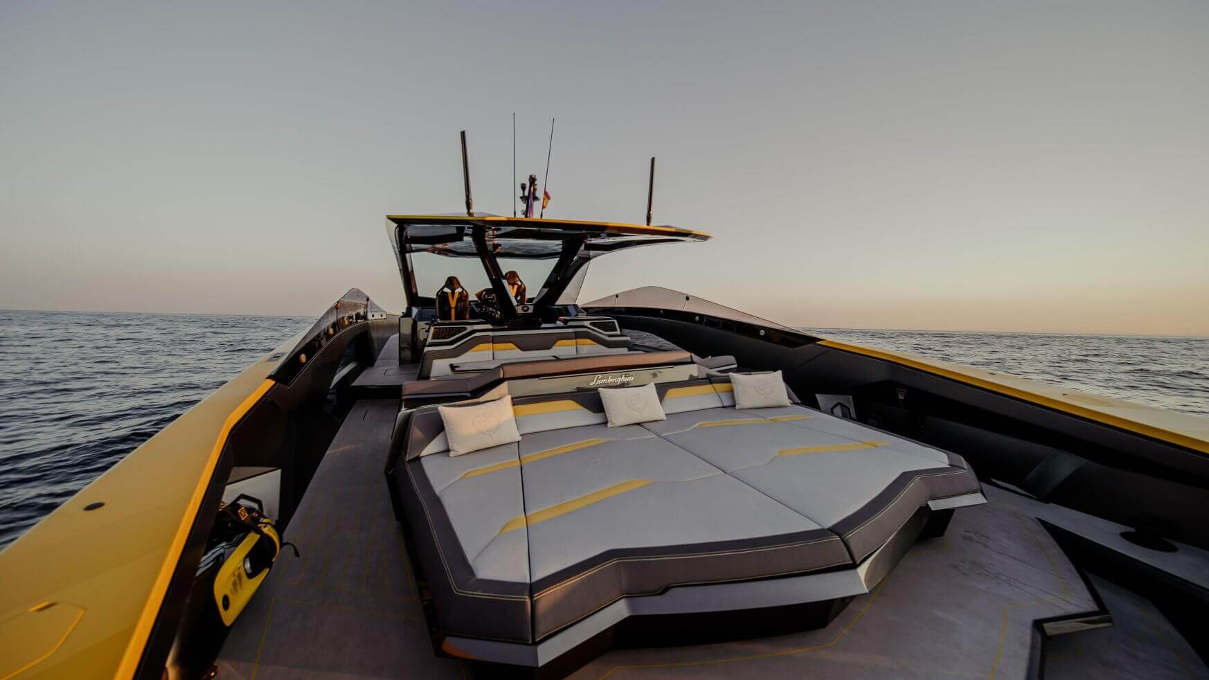 Een luxe speedboot van Lamborghini met een ruime lounge op het achterdek bij zonsondergang.