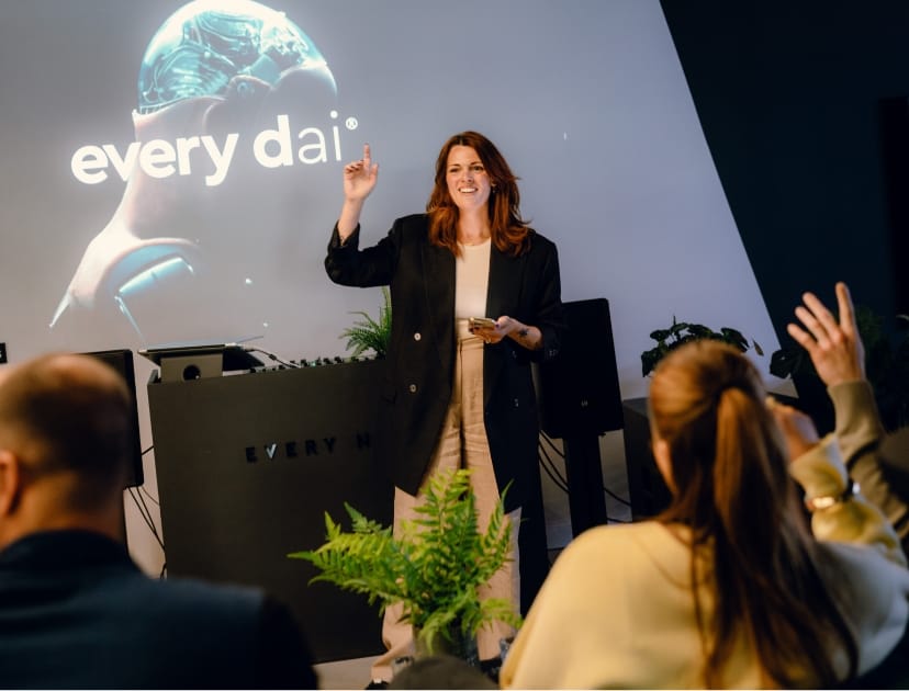 Een vrouw geeft een presentatie aan een publiek, staand bij een scherm waarop 'elke dag' wordt getoond.
