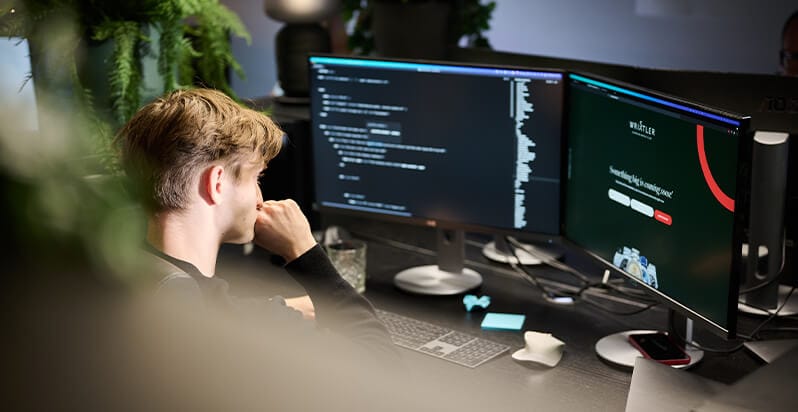 Aan een met planten gevuld bureau programmeren en bedenken ze op twee schermen strategieën voor "website laten maken roosendaal".
