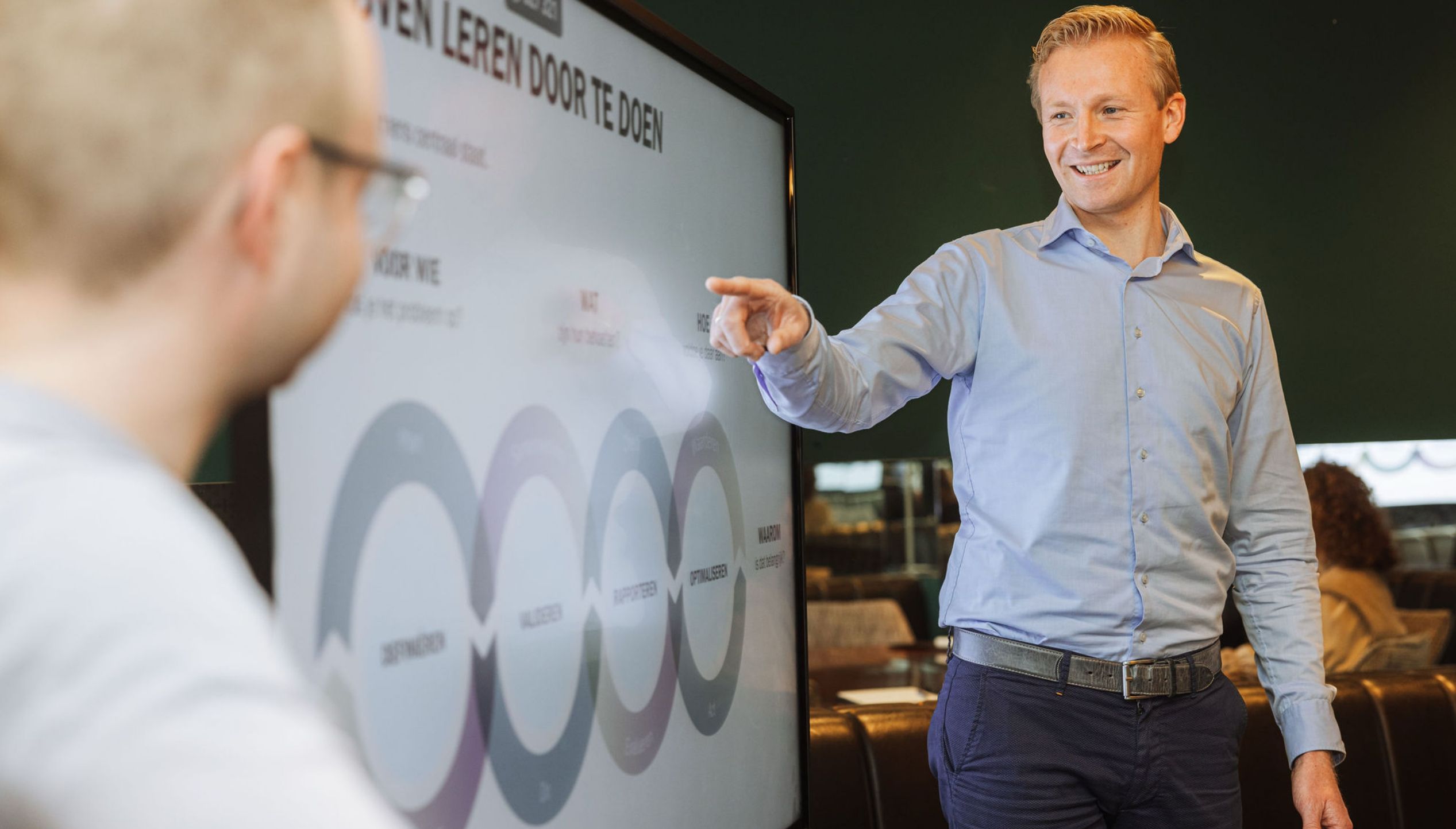 Een vertegenwoordiger van de FIT Group presenteert een kleurrijk diagram terwijl iemand anders aandachtig luistert.
