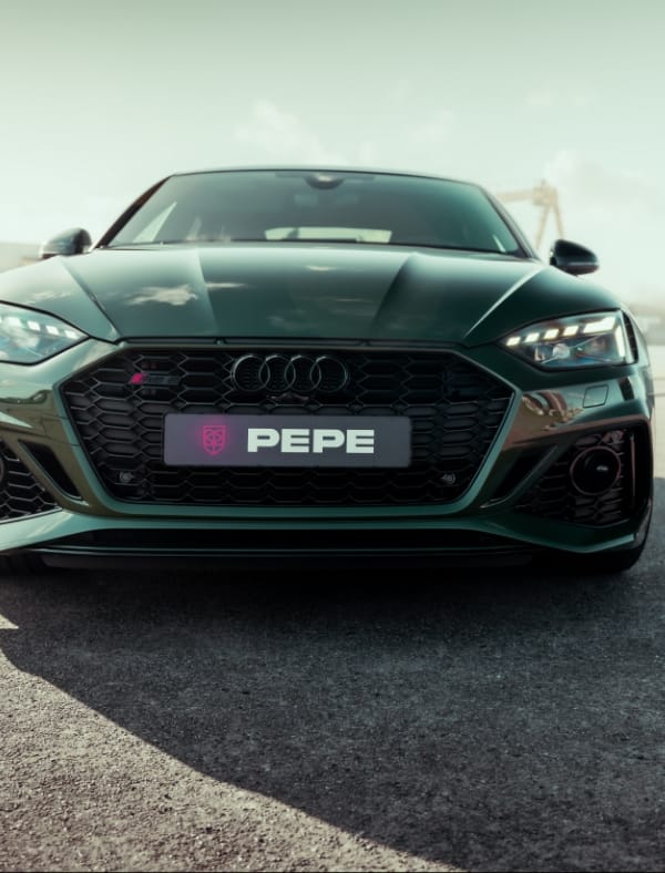 Donkergroene Audi met speciaal PEPE-kenteken, geparkeerd bij Koppert Cress. Vooraanzicht op de stoep.