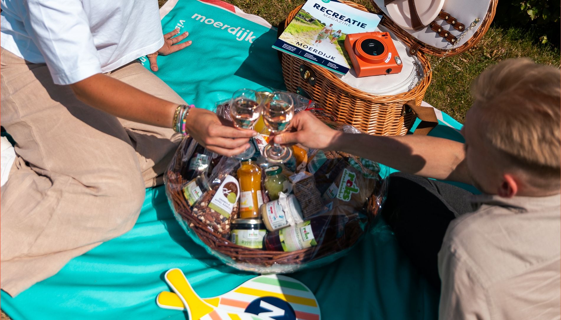 Proost op een picknick: eten, drinken, een camera en Memphis Depay kleding voor een stijlvolle outdoor vibe.