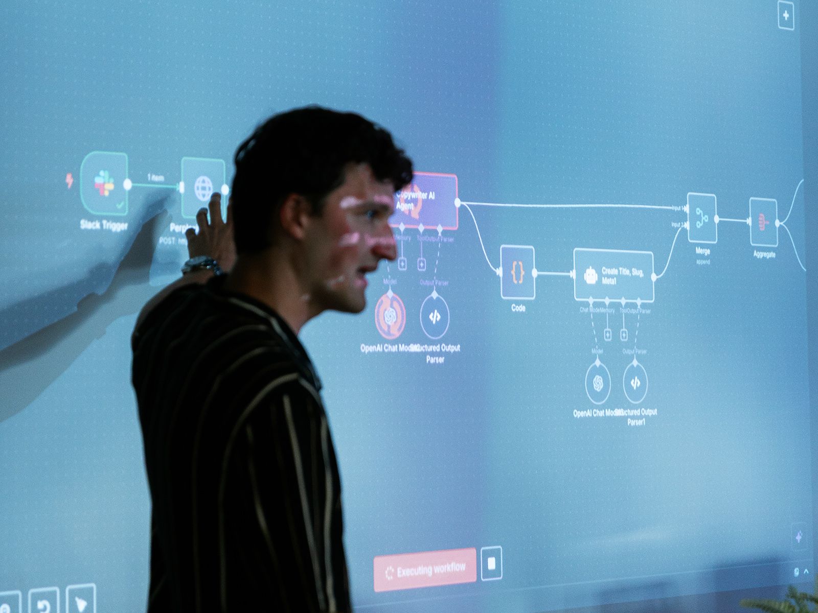 Iemand wijst op een workflowdiagram dat tijdens een presentatie op een scherm wordt weergegeven.