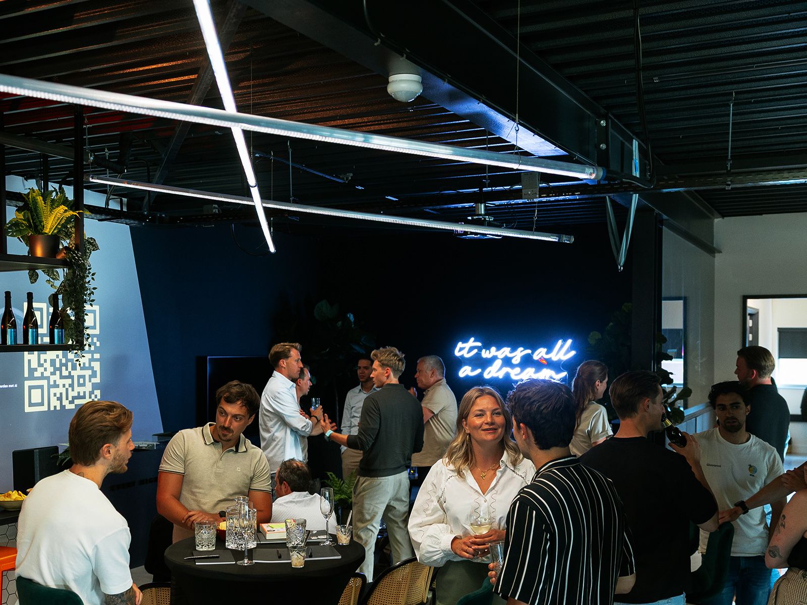Groep die binnen rondhangt met een neon "het was allemaal een droom"-bord op de achtergrond. Moderne sfeer.