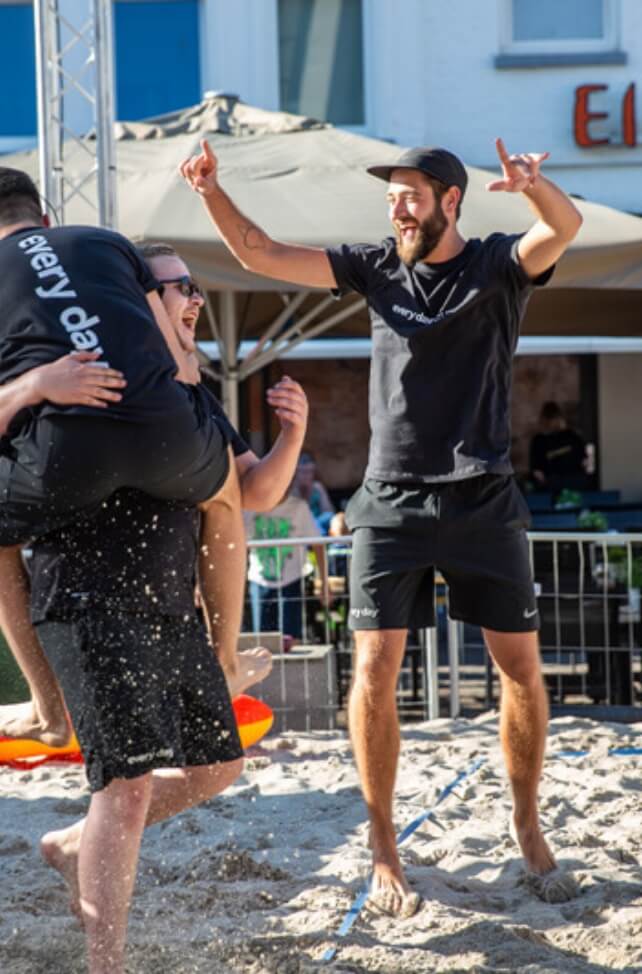 Mannen in het zwart vieren feest op een zanderige baan.