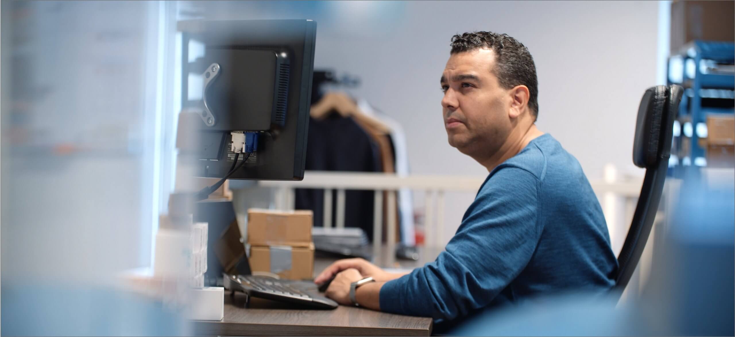 Een man in een blauw overhemd gebruikt Touchfix op zijn computer om taken op kantoor efficiënter te stroomlijnen.