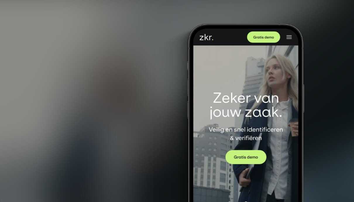 Smartphone toont app met Nederlandse tekst; zakenvrouw zichtbaar erachter.