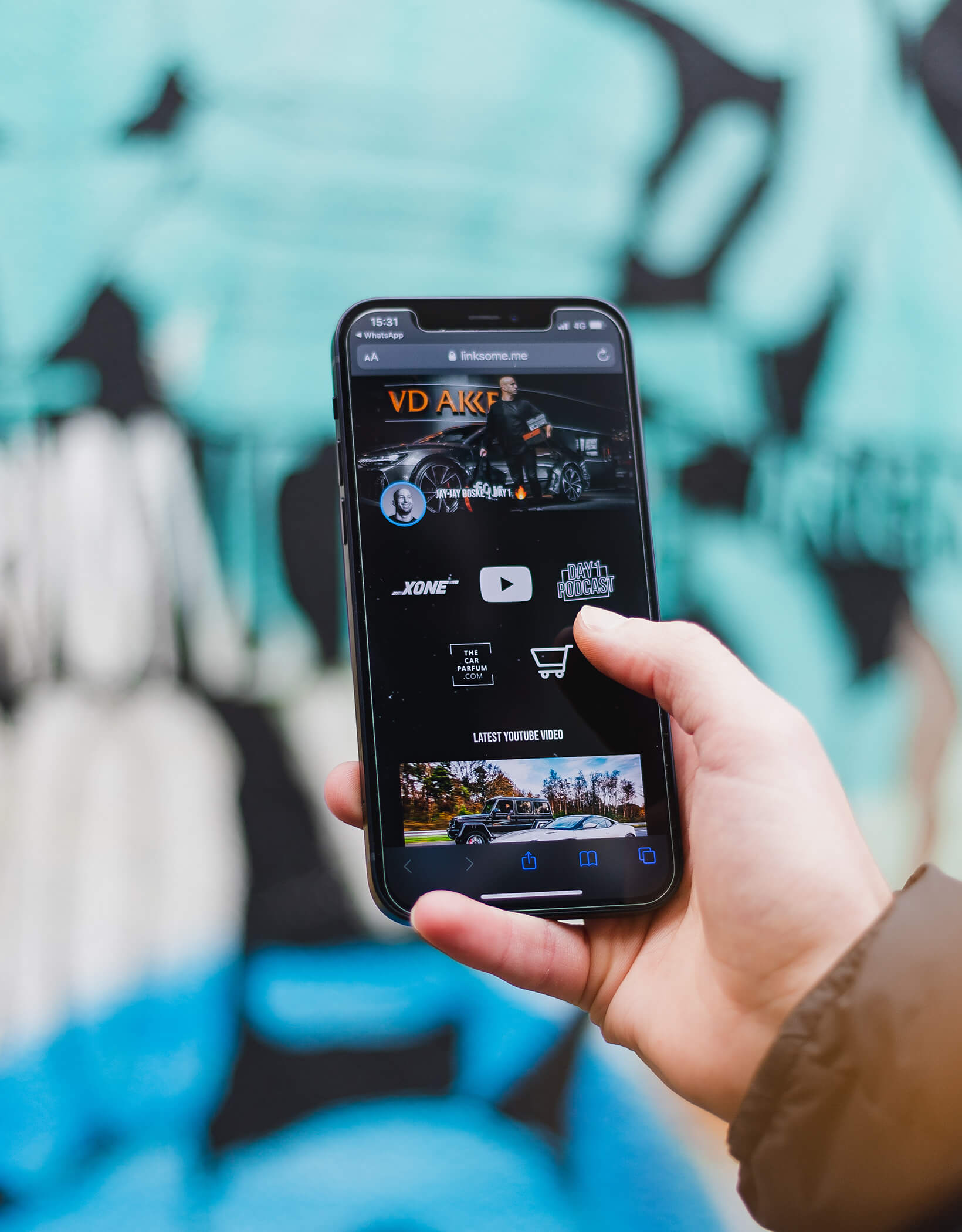 Smartphone met video en winkelwagentje tegen een blauwe graffitimuur.