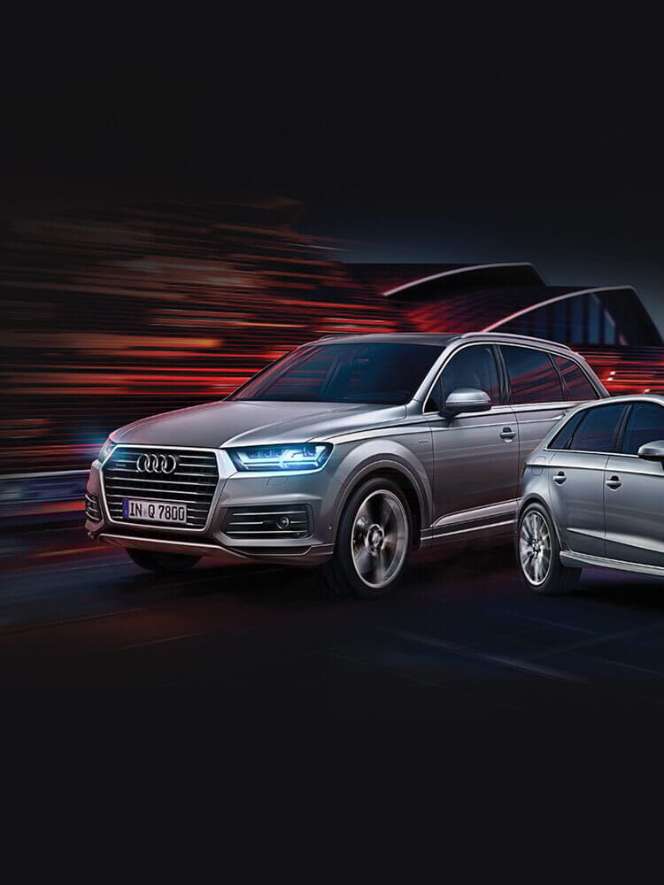 Twee zilveren Audi's, één SUV, racen over een donkere snelweg. Strakke kracht en elegantie kenmerken Audi Roosendaal.
