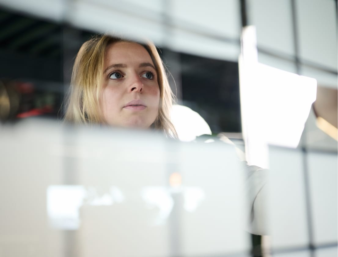 Een persoon schrijft aandachtig op een glazen wand die vol zit met plakbriefjes.