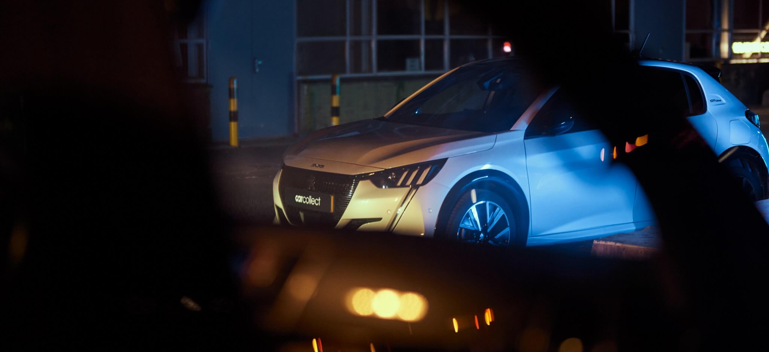 Een witte verzamelaarsauto gloeit zachtjes in de schemerige nacht, geparkeerd buiten.