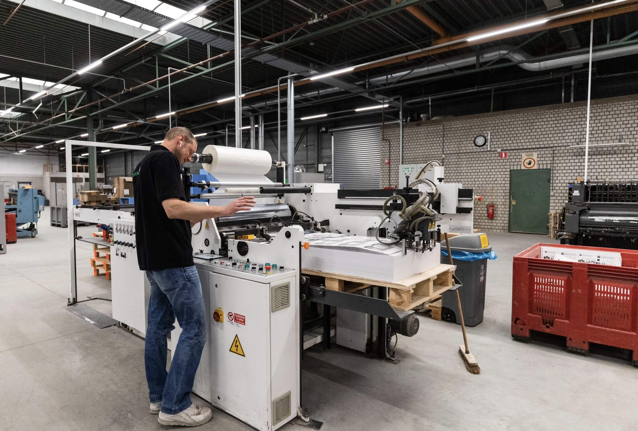 Fabrieksarbeider bedient een enorme drukmachine.