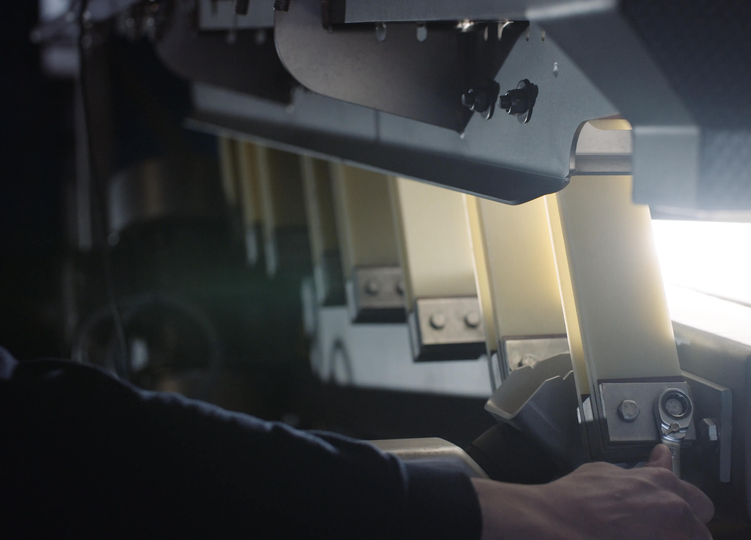 Close-up: persoon die industriële machines bij zacht licht afstelt.
