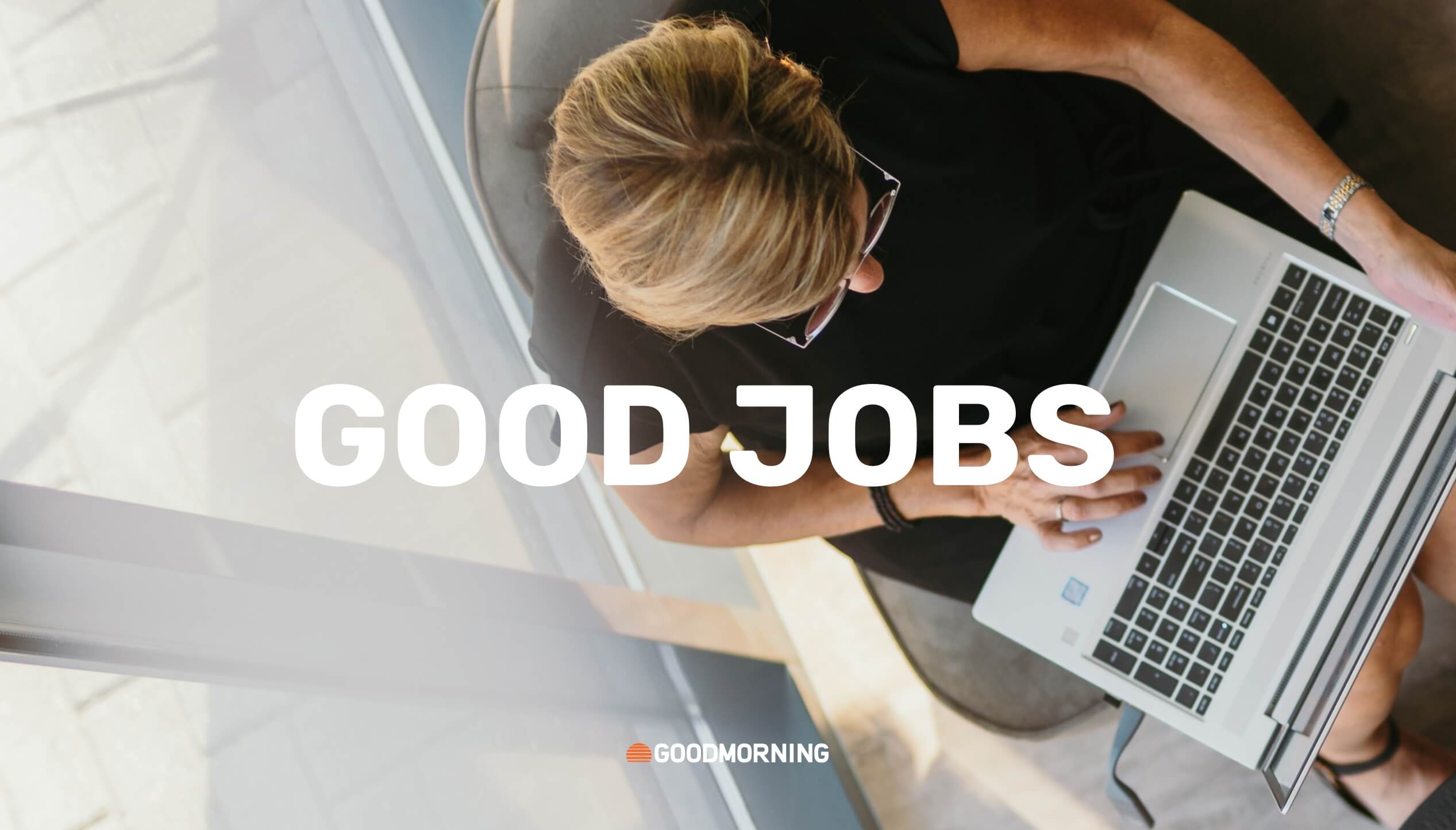 Bovenaanzicht van handen op een laptop, met op het scherm de tekst "GOED WERK".