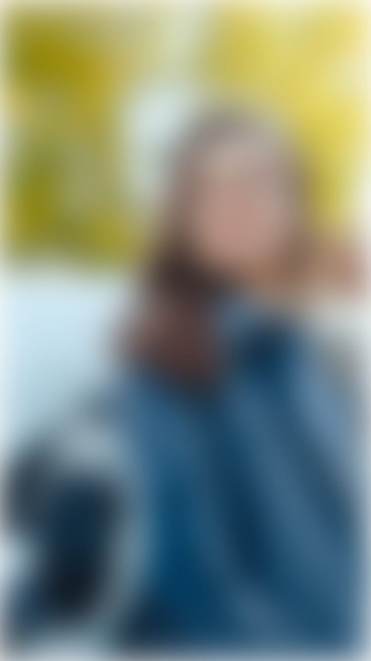 Een wintergekleed persoon staat in de sneeuw, met een boom achter zich.