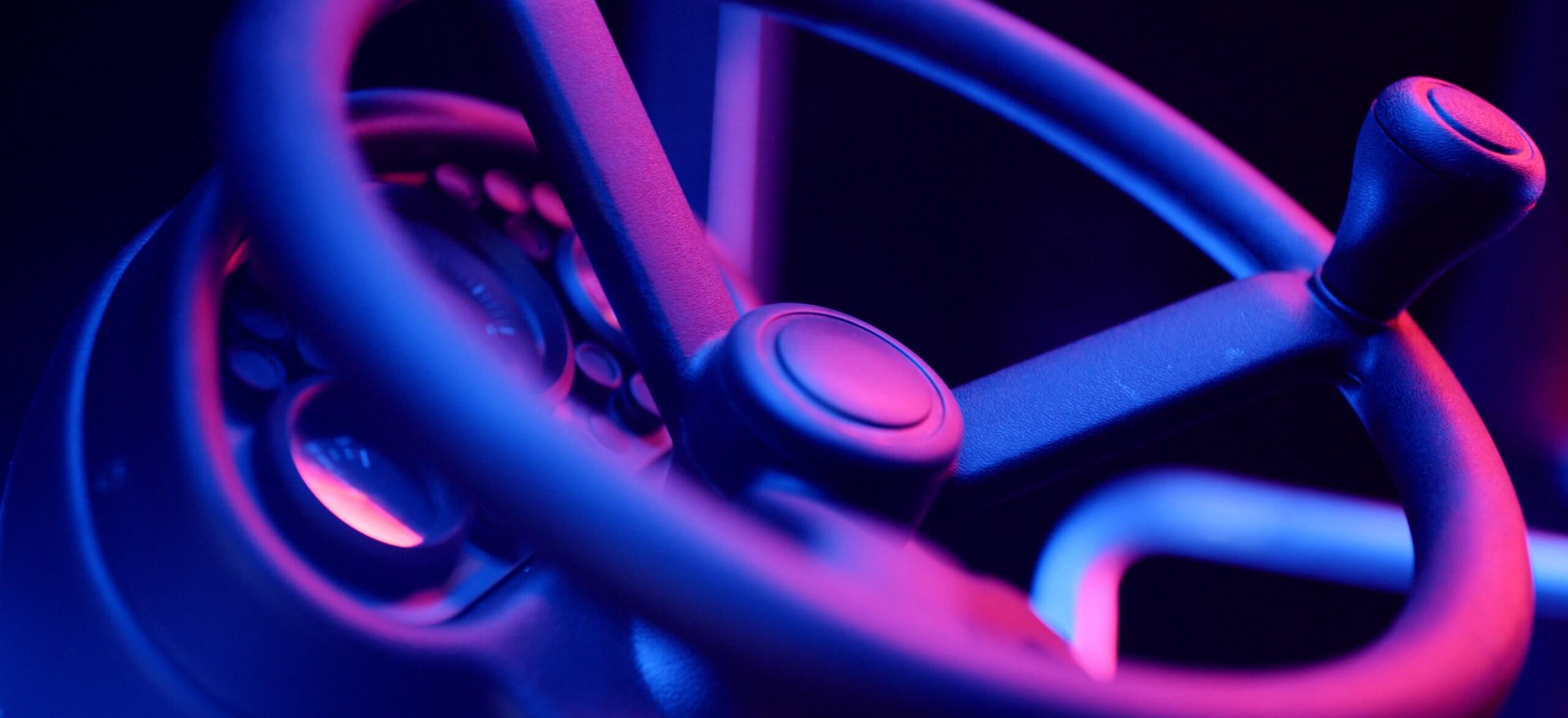 Het stuurwiel gloeit in fel paars en blauw neonlicht.
