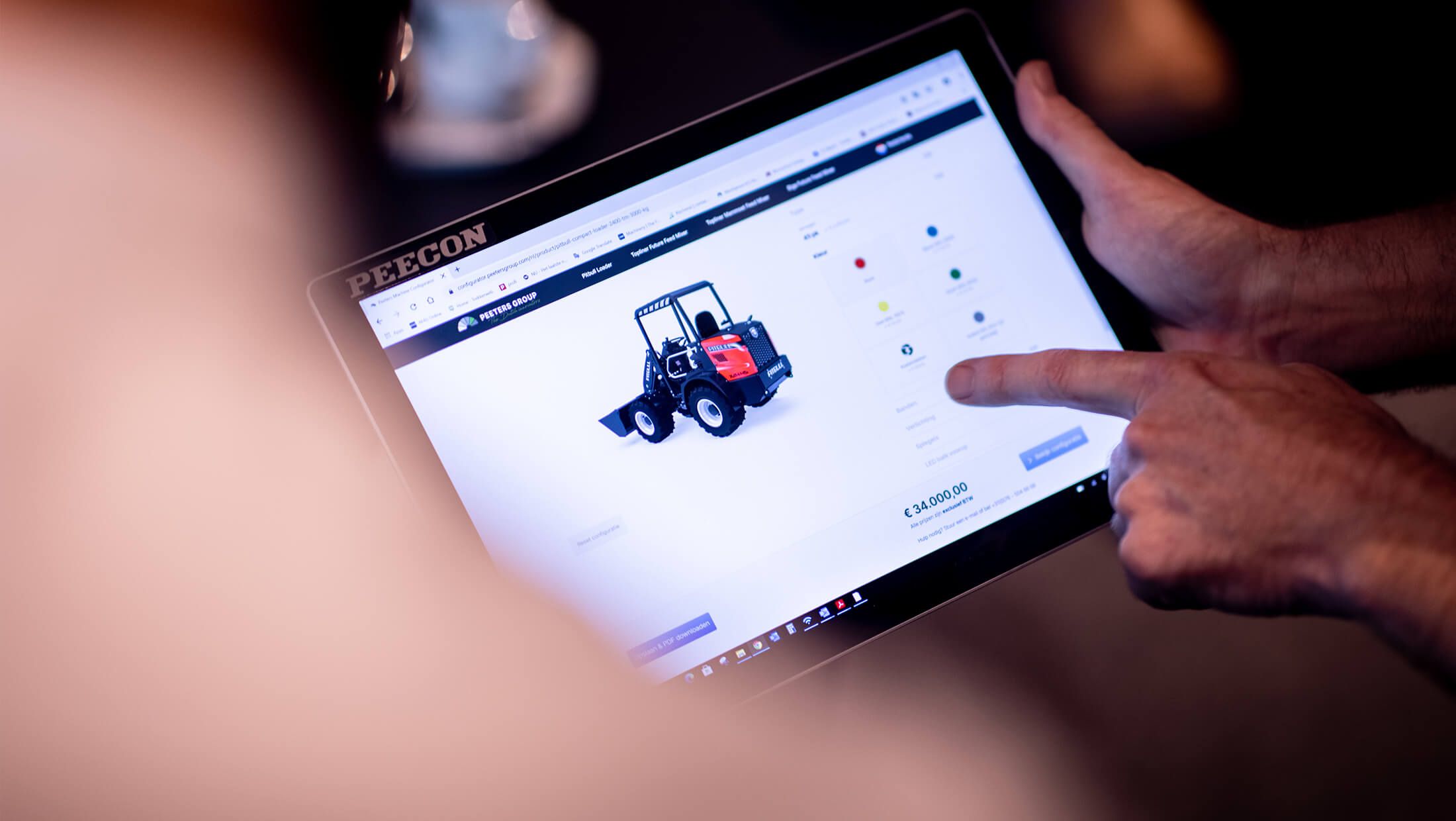 Een gebruiker bekijkt de website van Peeters Group op een tablet. Daarop staat een opvallend rood bouwvoertuig afgebeeld.