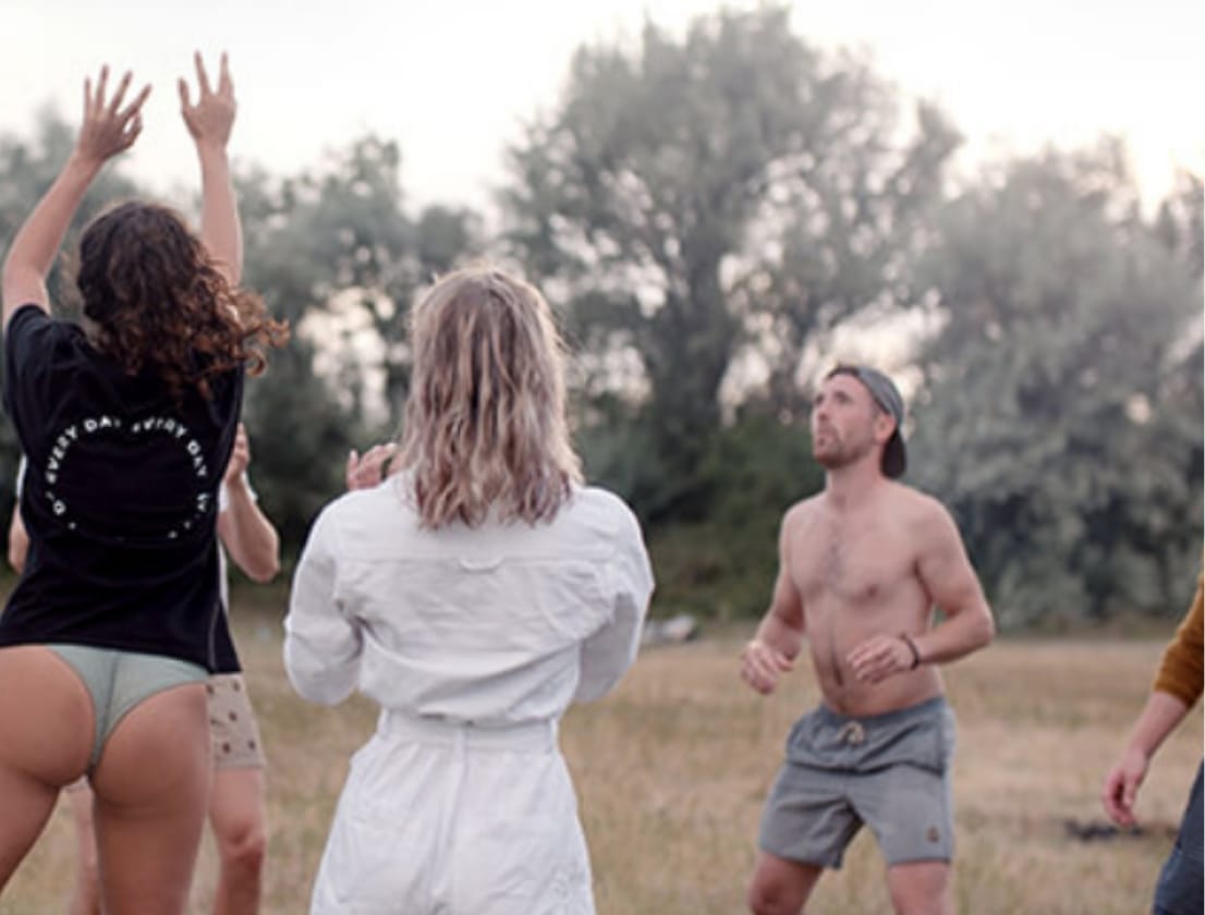 Volleybalveld in de buitenlucht op het gras met bomen op de achtergrond.