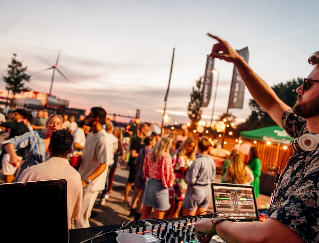 DJ draait op een zonsondergangsfeest terwijl het publiek geniet van de sfeer.