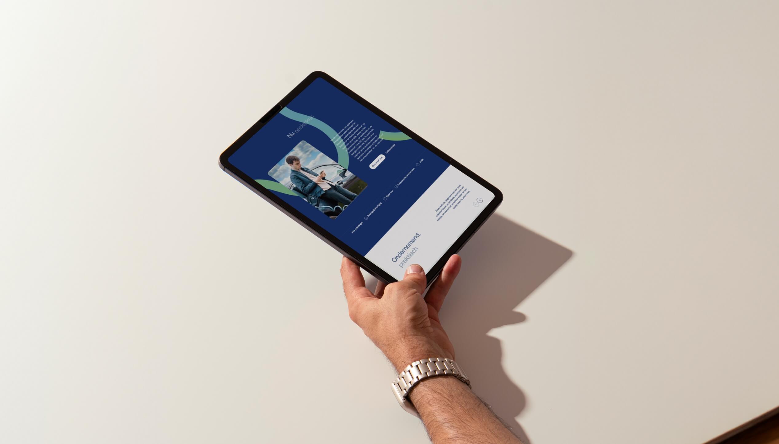 Op het tablet in de hand staat een webpagina met een afbeelding en tekst tegen een lichte achtergrond.