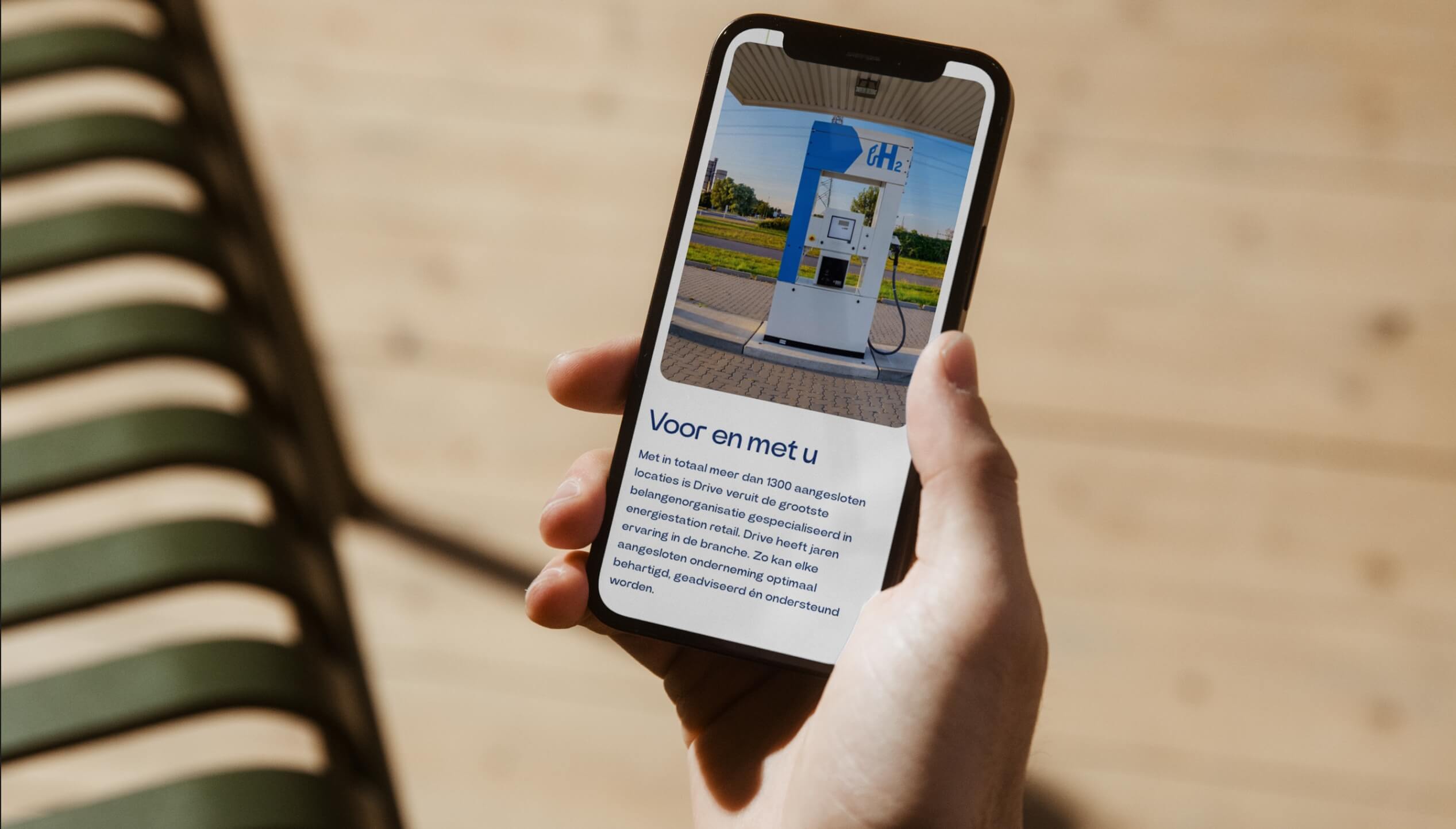 Persoon toont smartphone met afbeelding en informatie over een CNG-tankstation.