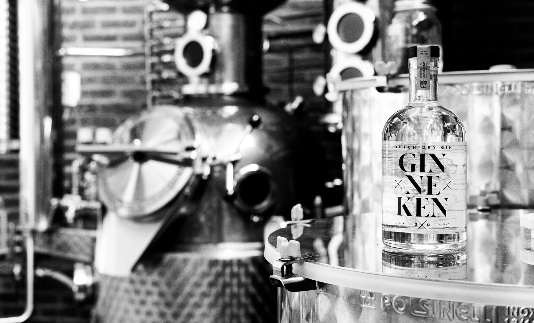 Bekijk een zwart-witfoto van een ginstokerij met een Gin Ne Ken-fles. Meer informatie op GinnekenGin.com.