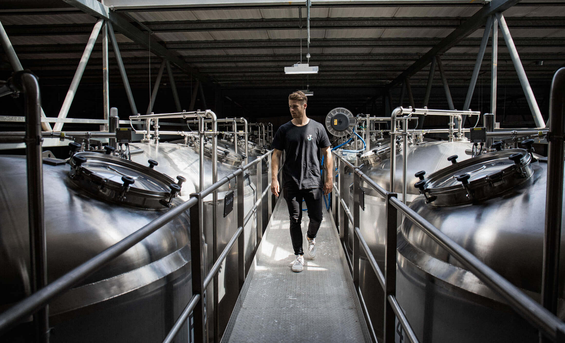 Er loopt iemand rond tussen de gigantische zilveren tanks van Jubel Beer.