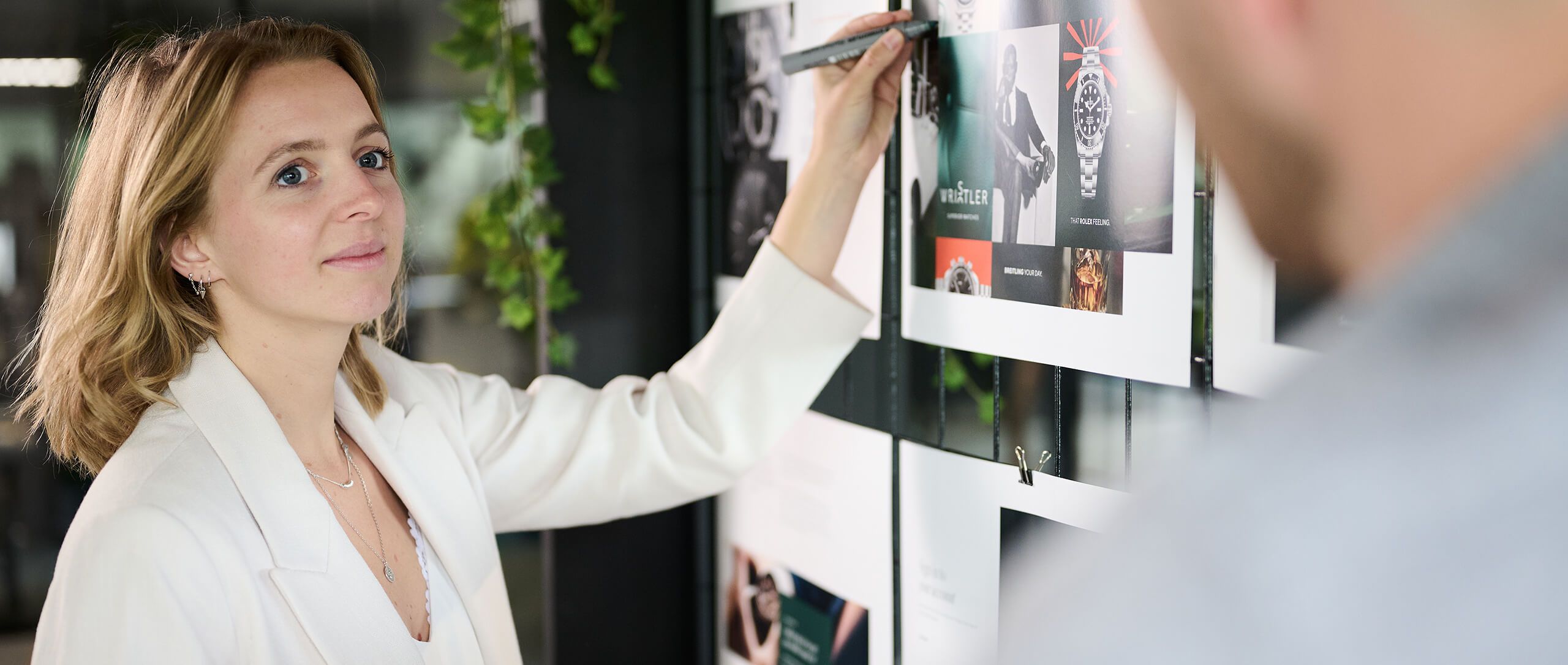 Vrouw in wit jasje schetst ontwerpen op een whiteboard.